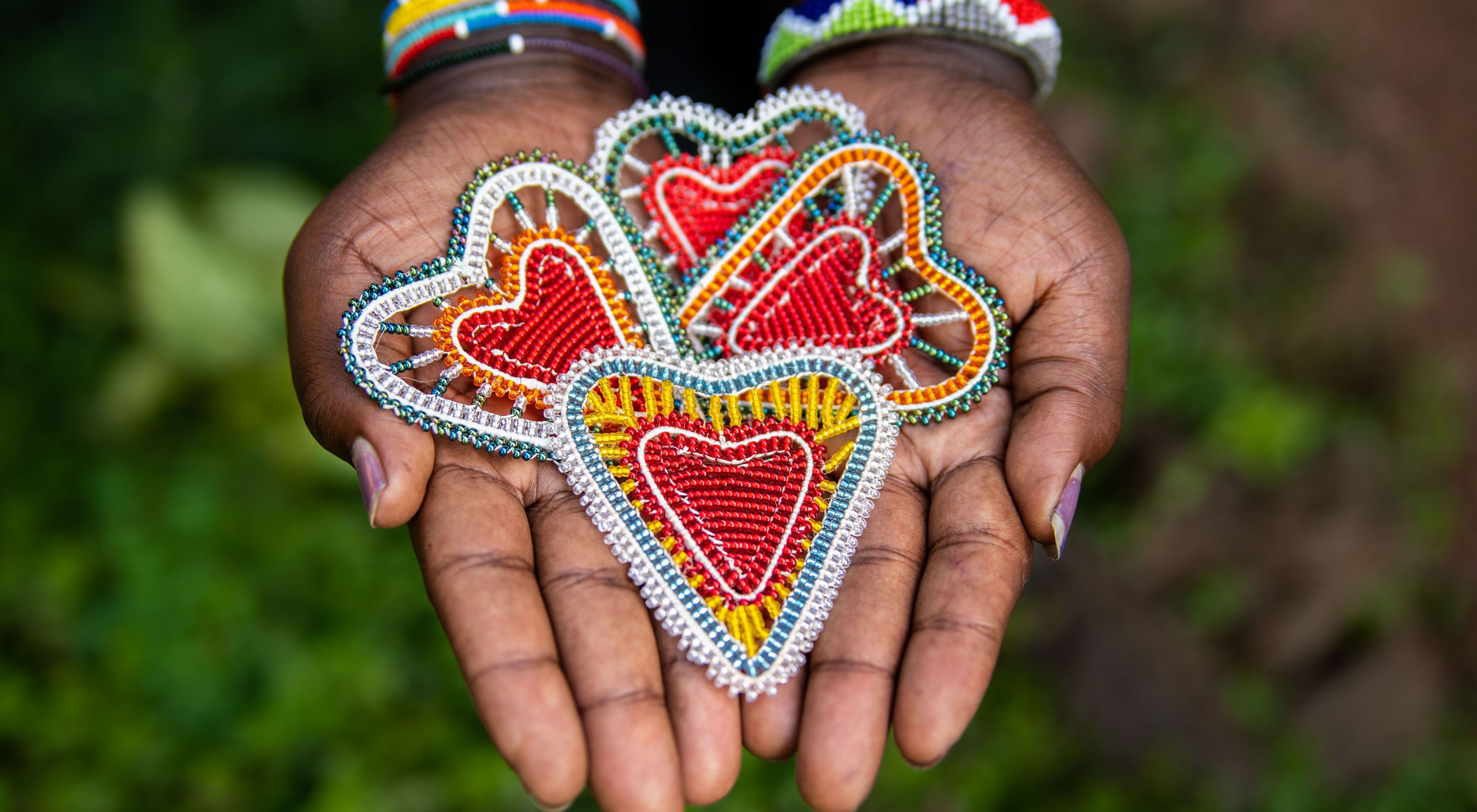 Hands hold beaded hearts made by Northern Rangelands Trust-Trading's BeadWORKS artisans in Kenya.
