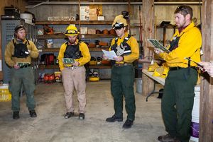 A group of four staff members in protective burn gear standing indoors.