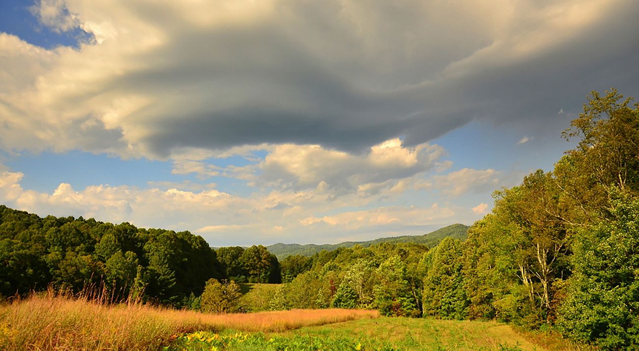 Blue skies and white clouds frame a colorful and lush mountain valley.