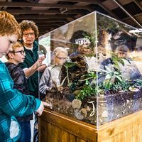 Volunteer talks to youth about an exhibit in a glass container at Bissell Nature Center in Ashtabula County.