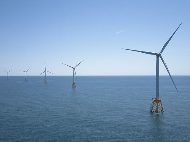 Una vista de cinco turbinas de energía eólica marina, con la turbina de la derecha en primer plano y la turbina más a la izquierda al fondo.