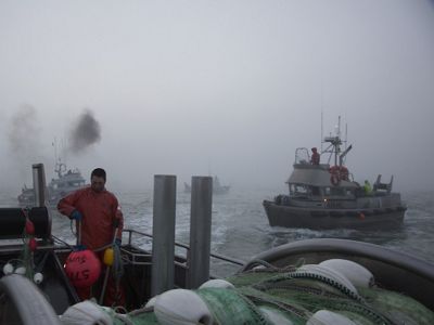 Commercial drift boats gather in one location and people onboard prepare to begin fishing in Bristol Bay.