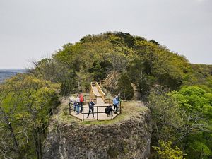 A drone shot of the peak of Buzzardroot Rock with people waving from the platform at its peak.