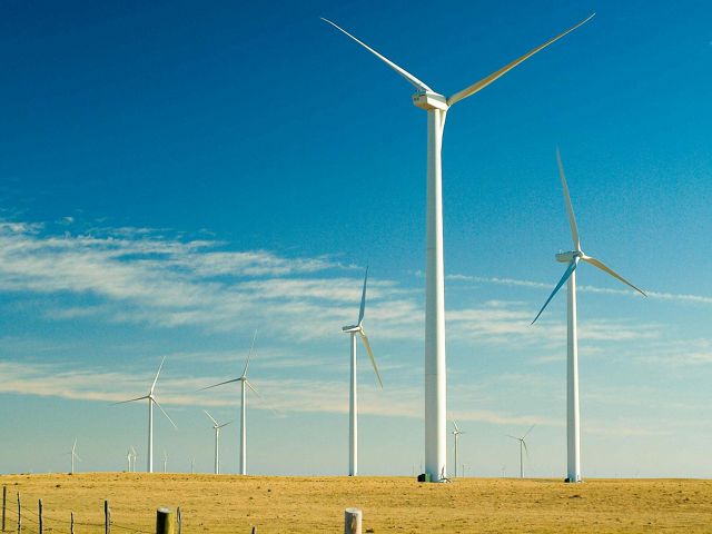Five large wind turbines standing on grassland plains.