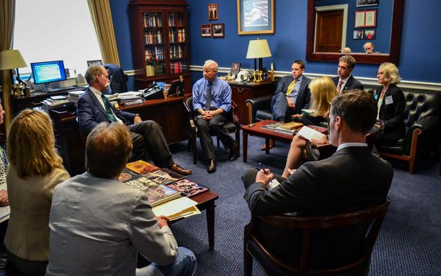 A group of people sitting in a circle in a politician's office, asking questions.