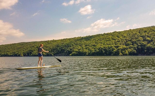A person standing on a paddle board with an oar on the water.