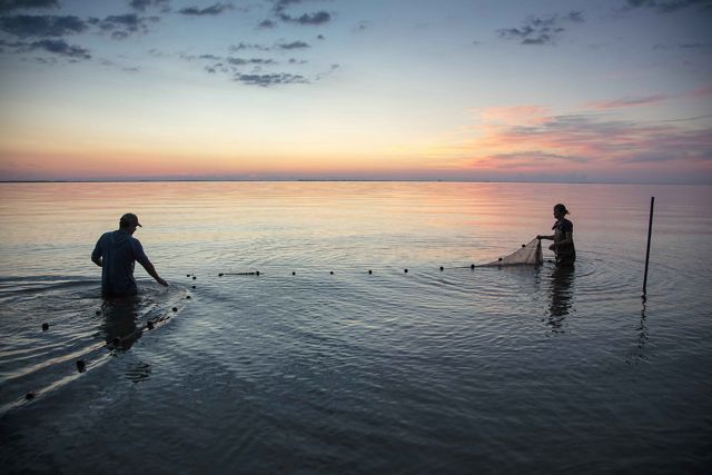 Photo at sunset of two people managing nets in Lake Michigan.