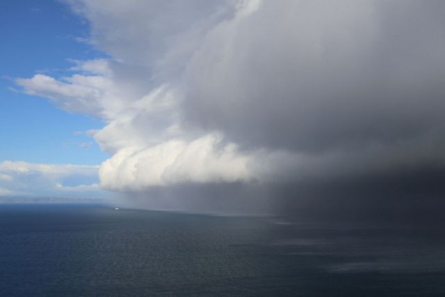 Storm clouds move across the sea and sky with a boat about to be overtaken in the distance.