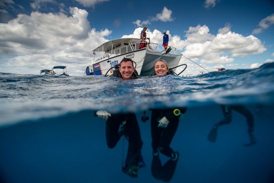 TNC staff members Joe Pollock and Ximena Escovar in the Caribbean Sea ready to dive and restore a coral reef.