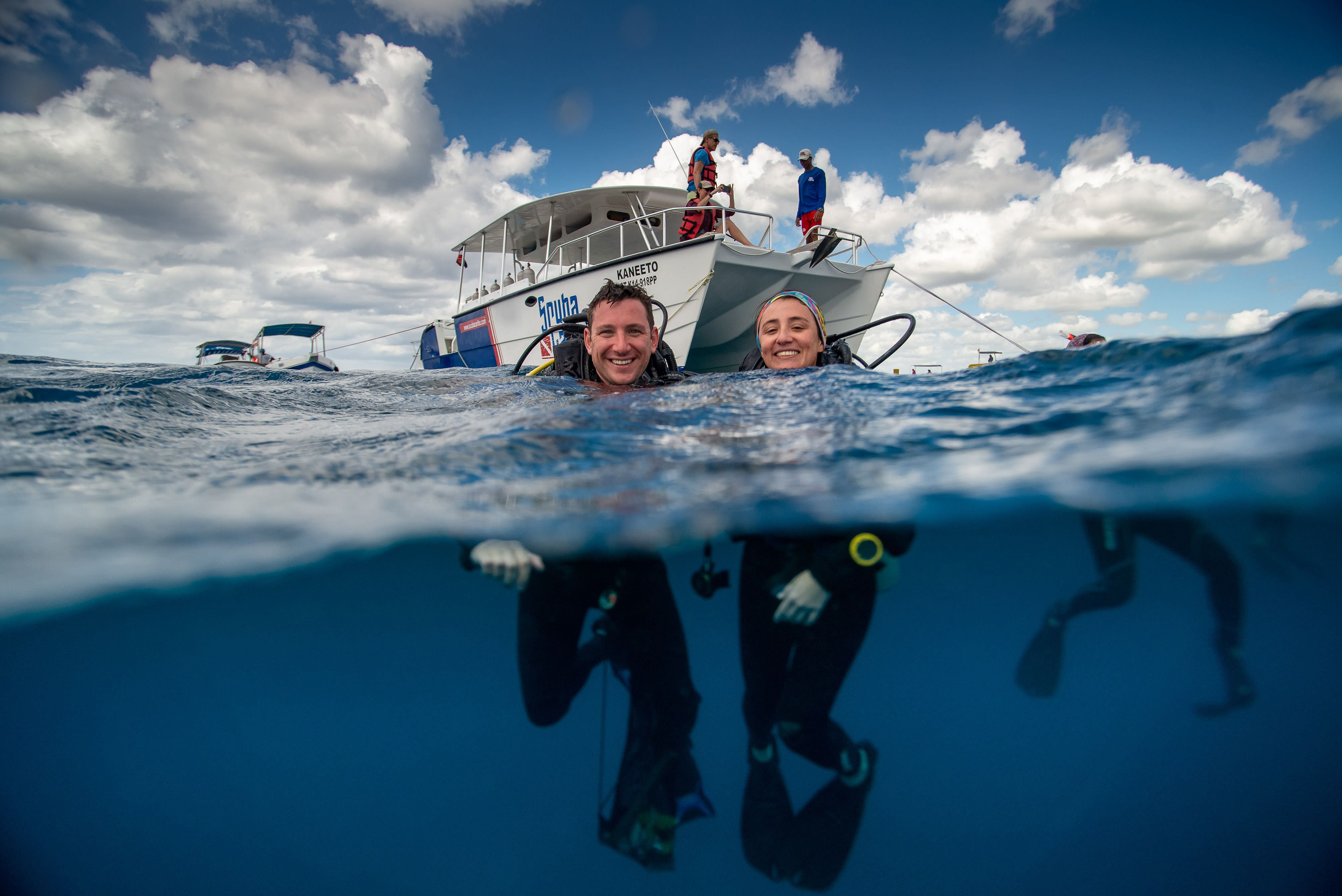 a man and woman in diving gear float in the water