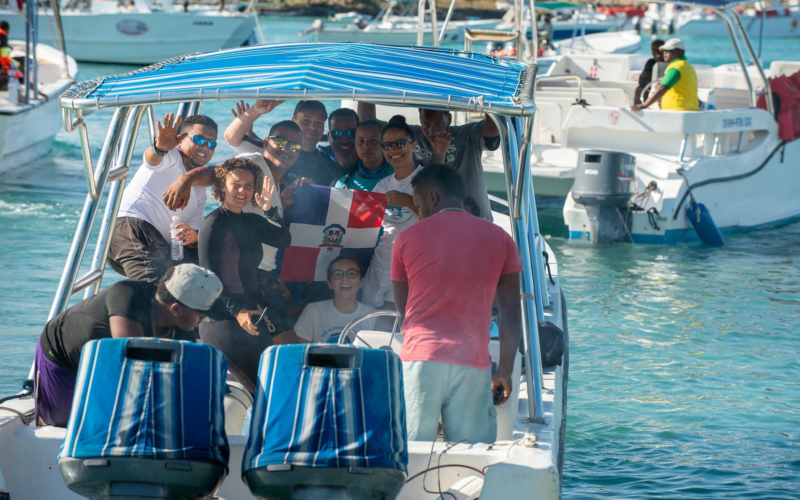 Rita Sellares, in her black wetsuit, and crew of divers wave goodbye as they set off to dive. 