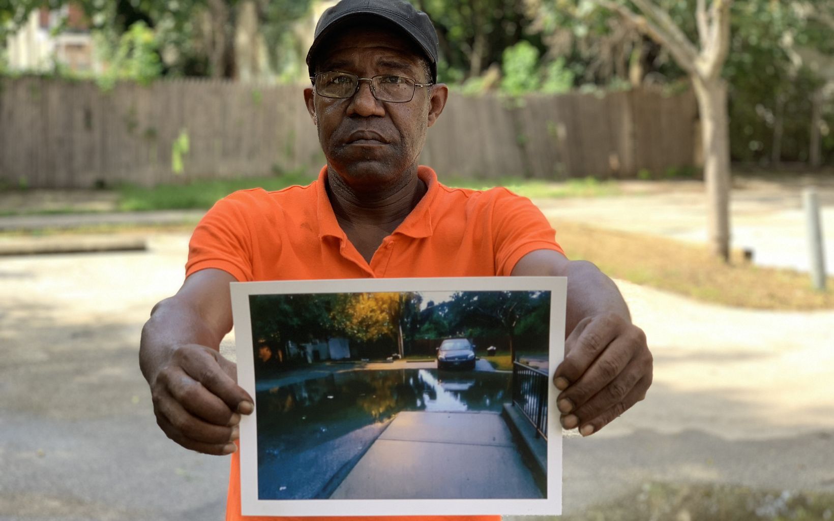 a man standing in the middle of a parking lot holds a photo of the parking flooded