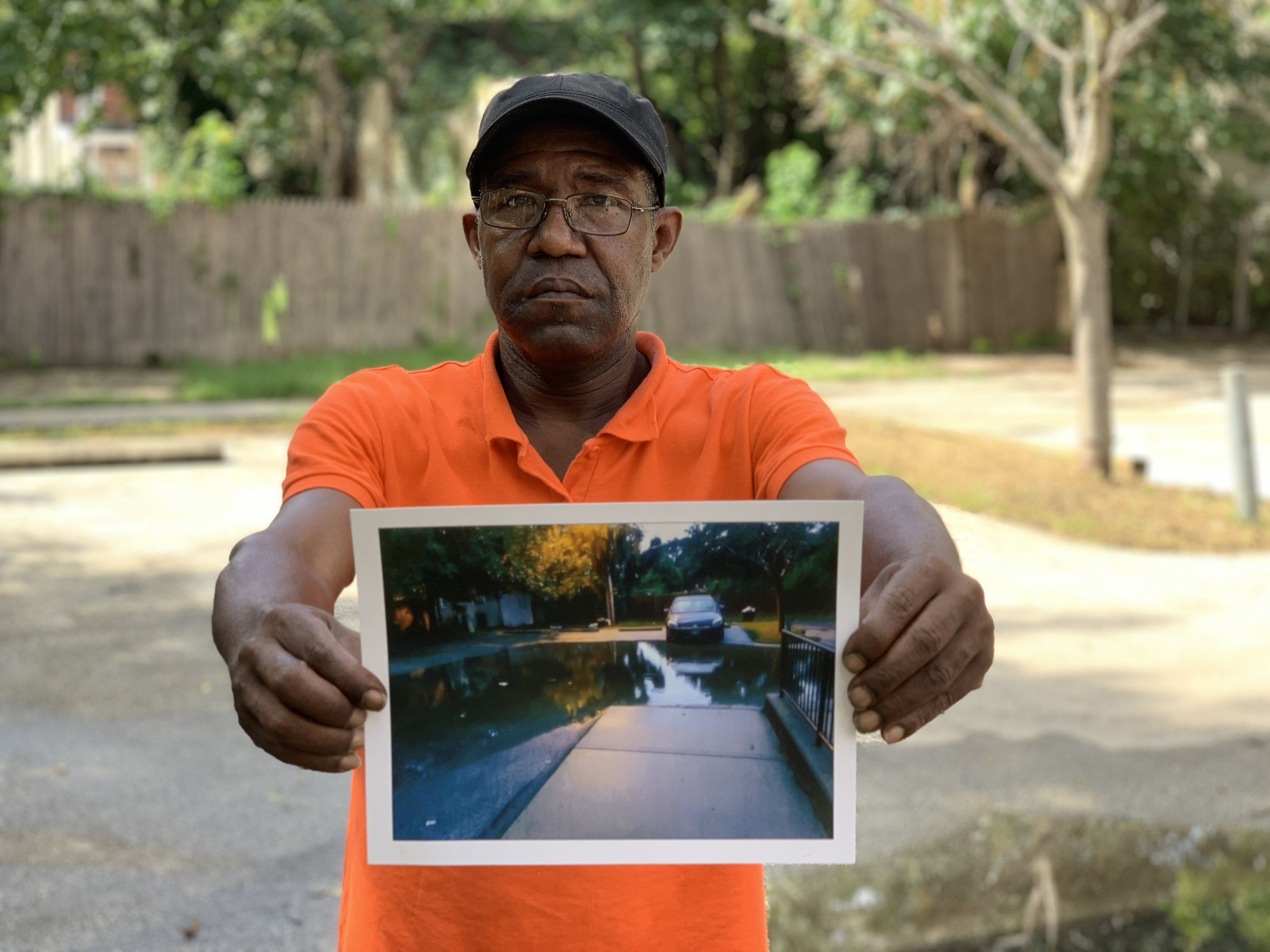 a man holds a picture of a flooded street