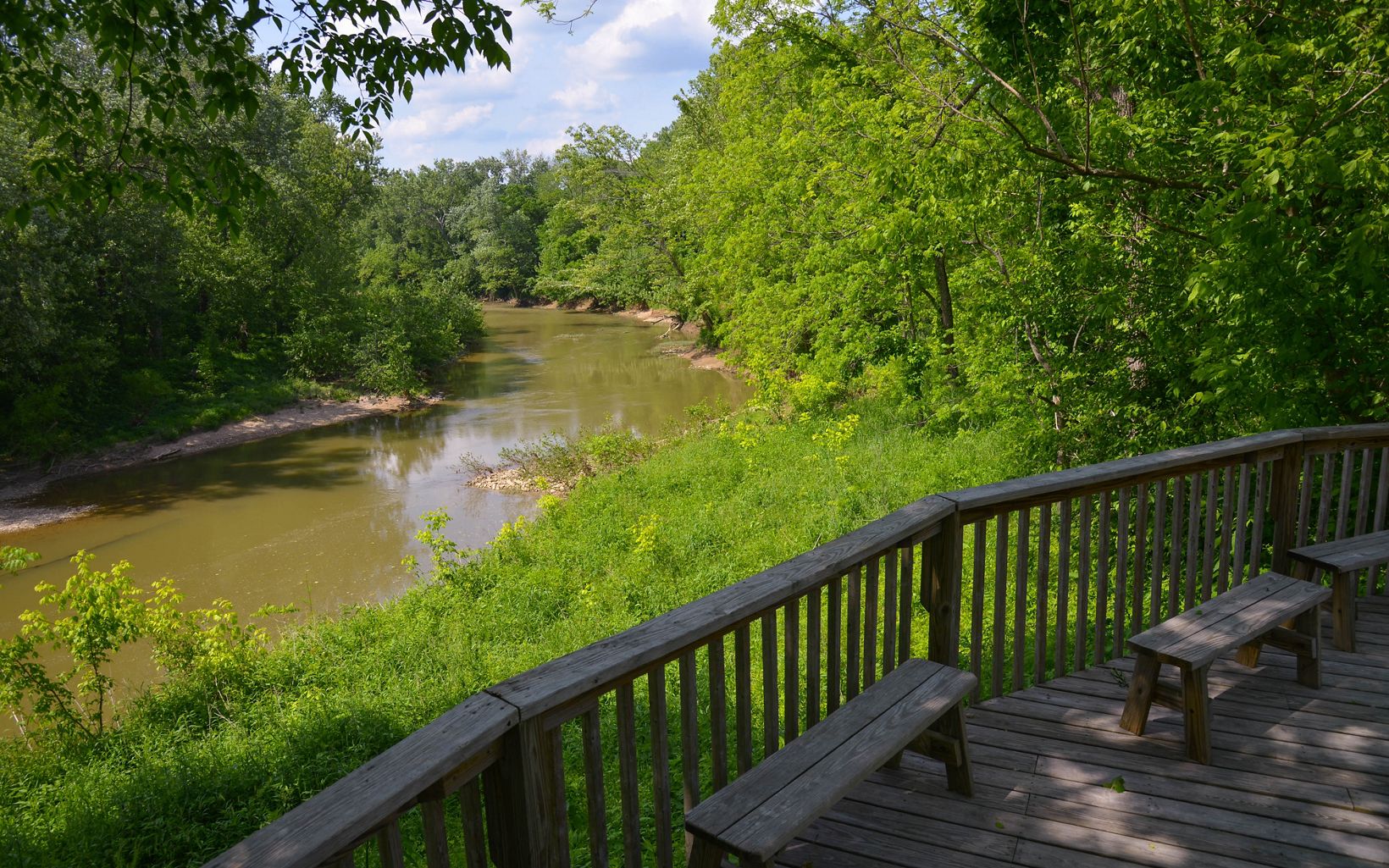 View from a wooden deck out over a slow-moving creek.