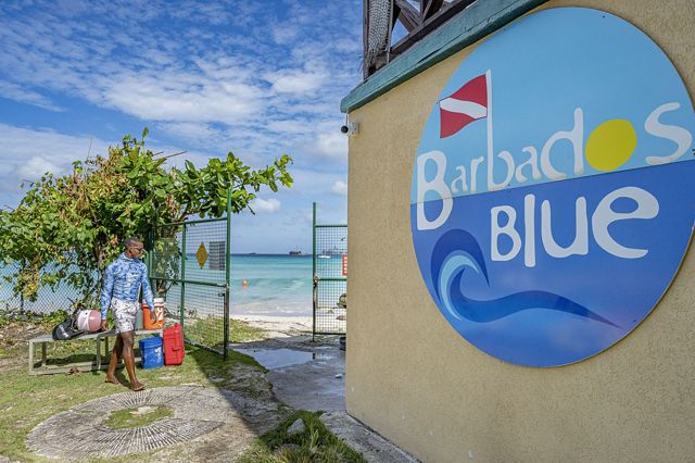 a man walking into a dive shop called Barbados Blue.