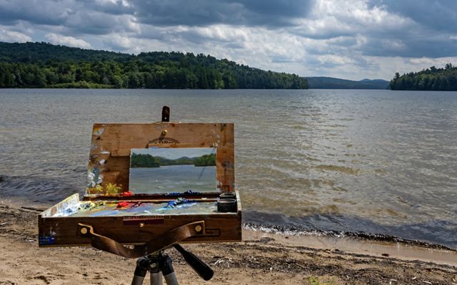 A canvas with a painting of the river in front of the river. 