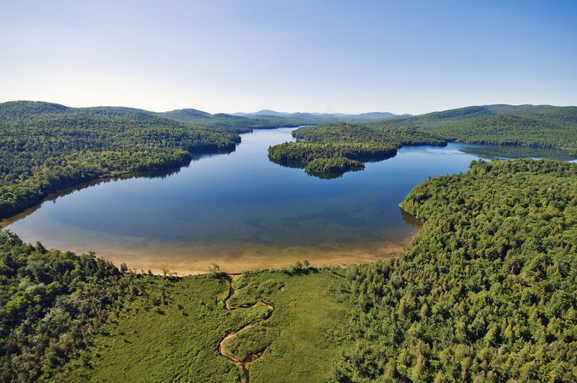 Aerial view of Follensby Pond surrounded by forest under clear sky.