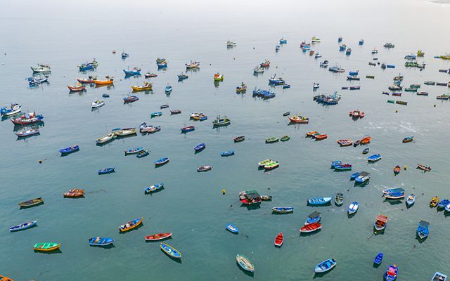 an aerial view of small, colorful fishing boats dotting the ocean