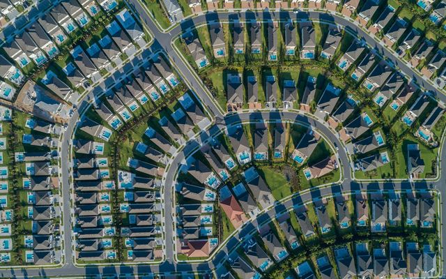 Aerial view looking directly down on an Orlando area neighborhood with densely packed houses, each with a backyard swimming pool, along curving suburban streets.. 