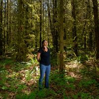 Kaylee Kenison standing in a forest of thick trees in Washington.
