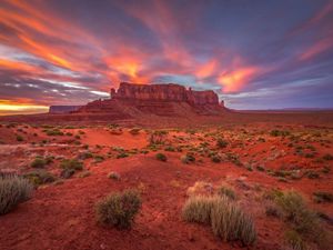 sunset over a red desert landscape with a tall mesa in the background