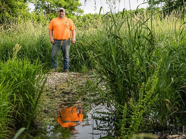 Farmer Jason Ward stands next to wetland on his farm.