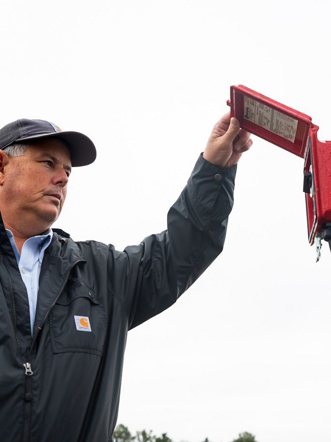 Man checks on a red irrigation pump timer in this field