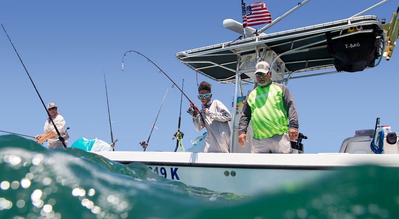 Three fisherman on a small boat with fishing lines in the water in Key Largo, Florida.