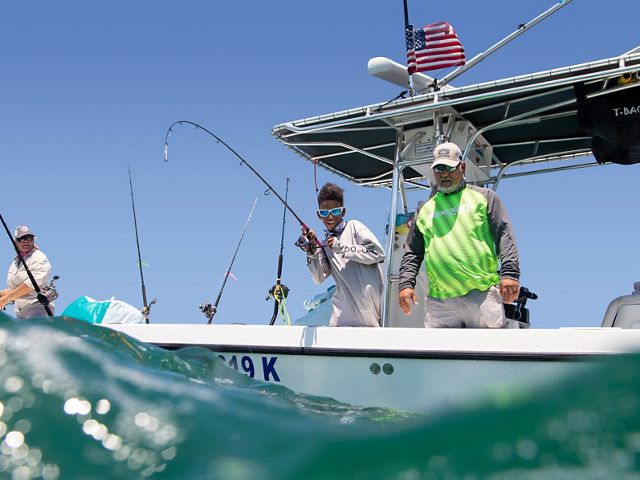 View from just above the waves of three people fishing from the side of a boat in the Florida Keys.