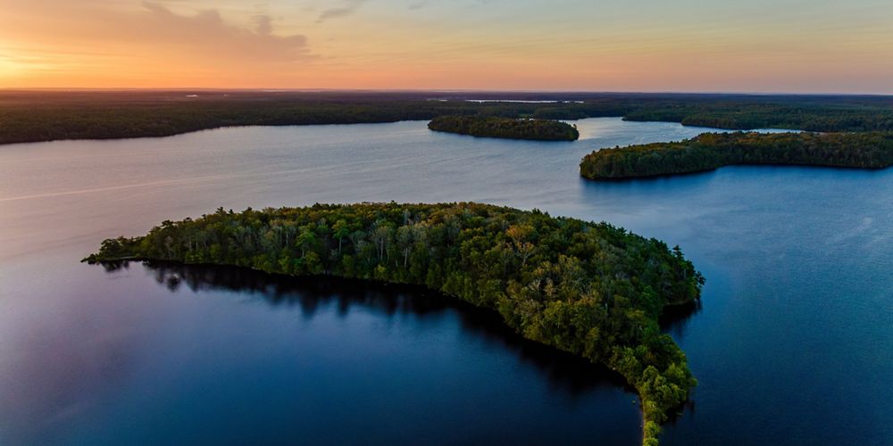 An aerial view of a freshwater area with small grassy areas in-between at sunrise.