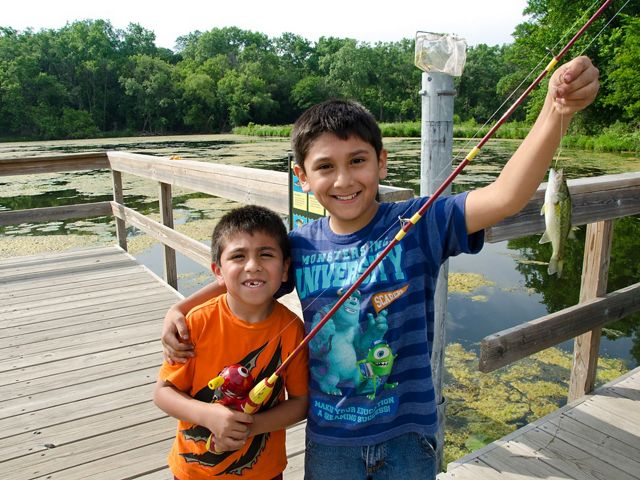 Two young boys hold up their catch from a fishing pier.