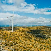 Photo of wind turbines dotting yellow rolling hills in Croatia.
