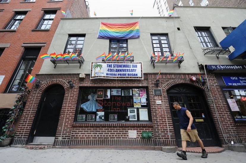 Un hombre pasa frente a la tienda de negocios urbanos del Stonewall Inn de Nueva York. Dos puertas arqueadas flanquean un amplio ventanal.