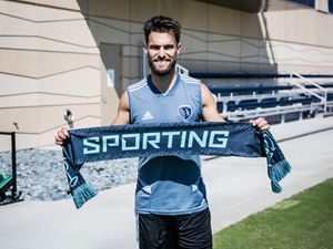Sporting Kansas City's Graham Zusi holds a Sporting Sustainability match scarf. 