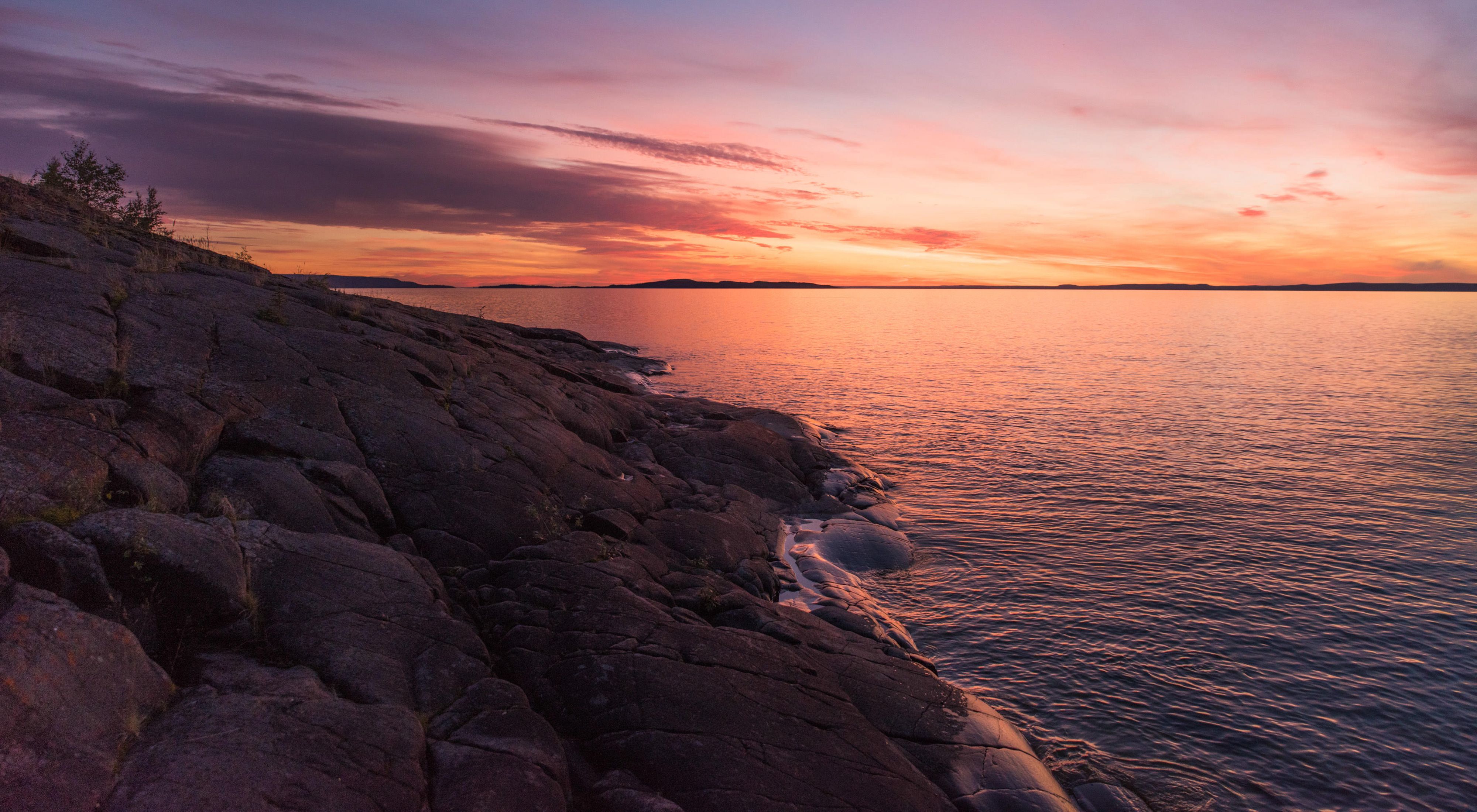 the sun sets over the rocky shoreline of great slave lake, a cold-water lake in Canada's Northwest Territories