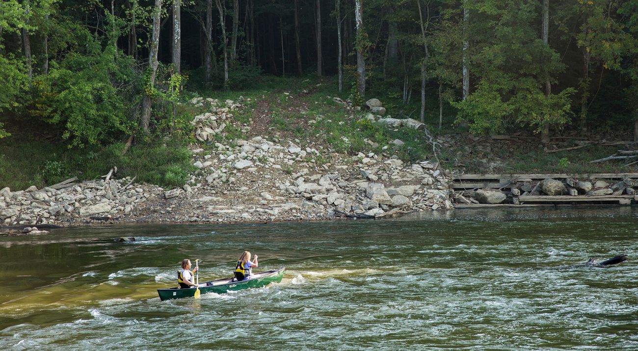 Two people on a canoe go over some light rapids in the Green River.