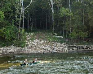 Two people on a canoe go over some light rapids in the Green River.