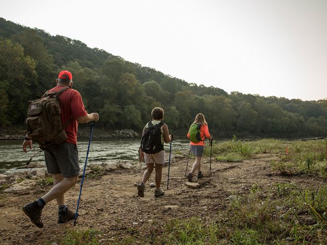 Hikers walk along the Green River as it flows through a vegetation lined shoreline.