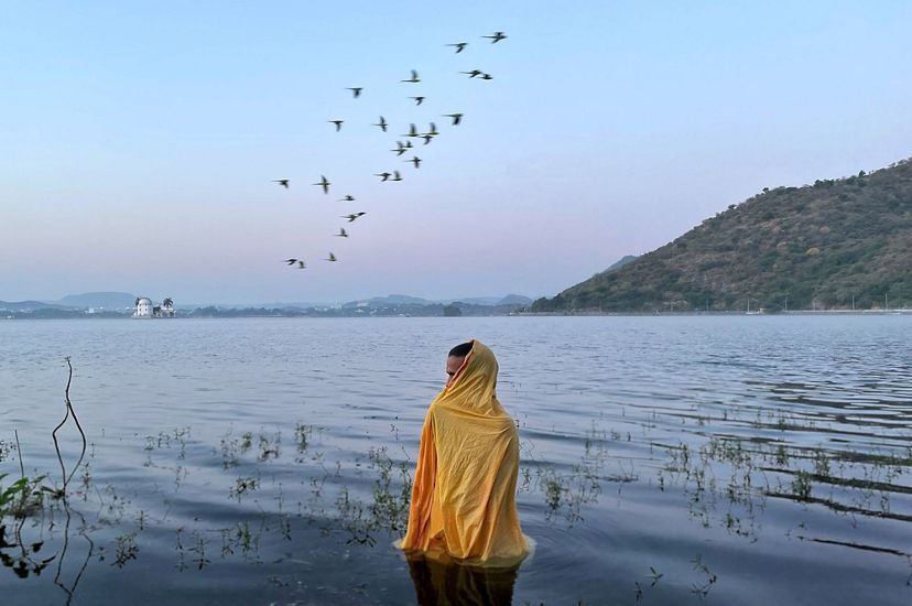 A man standing in freezing cold water waiting for Sun God to arrive during Chatth Puja Festival.
