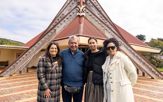 Four people stand and pose for a photo outside a traditional building.