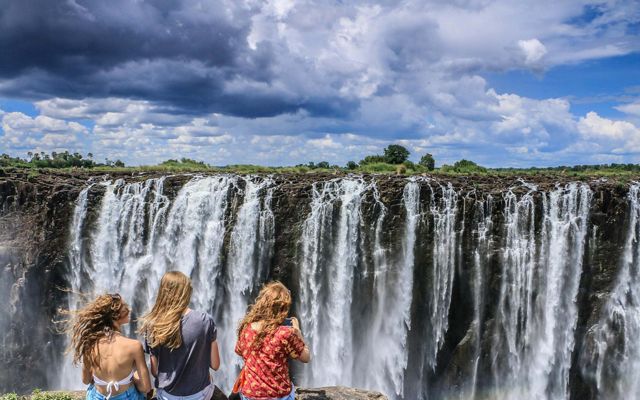 Three woman look out at Victoria Falls, between Zimbabwe and Zambia. 
