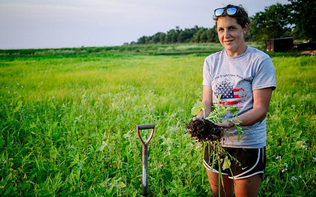 Farmer Allison Grimm holds up crop roots to show good soil health.