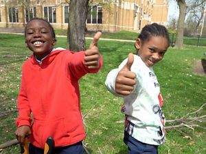 Two children giving a thumbs up outdoors.