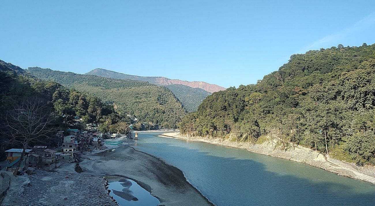 Dense forests line either side of a wide river in India.