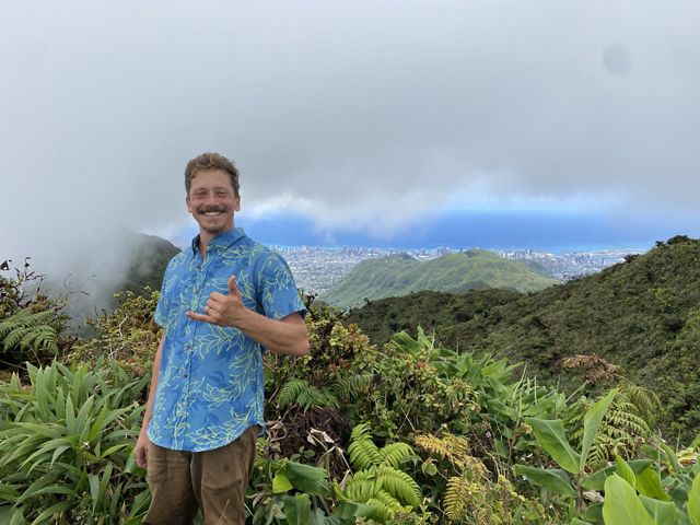 JC Watson stands atop a mountain in Hawaii.