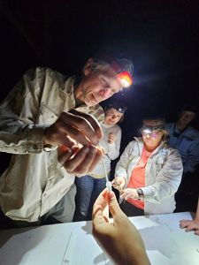 A man with a head lamp collects a specimen and puts a cotton swap in a tube.
