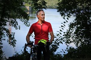 Josh Royte stands next to his bike with a river in the background.