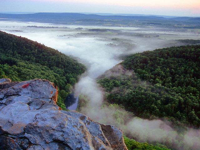 A mist emerges between two mountain ridges.