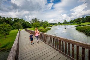 Child and mother crossing a boardwalk in a city park.