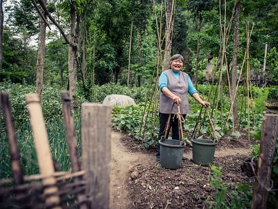 A villager carries buckets at a farm around Laohegou